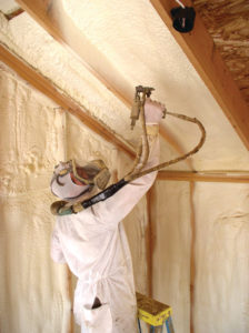 Person in Suit and Mask Spraying Spray Foam on Ceiling