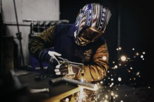 man in helmet welding pipes