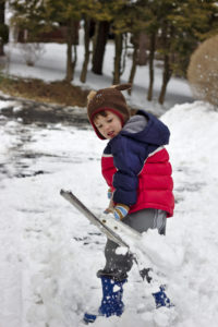 Little Boy in Warm Clothes Shoveling Snow