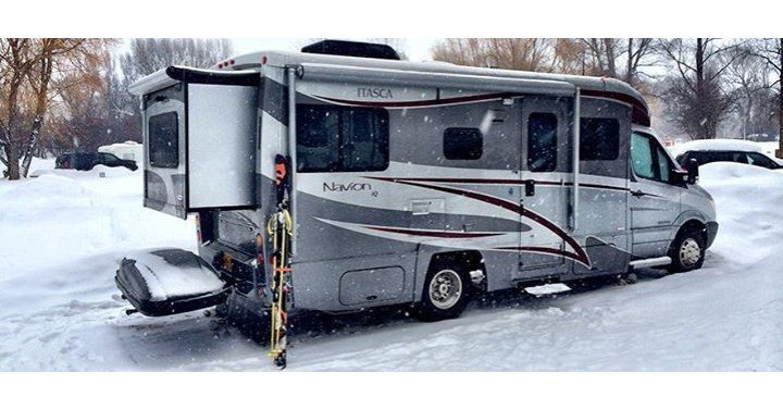 RV on snowy road with snow falling