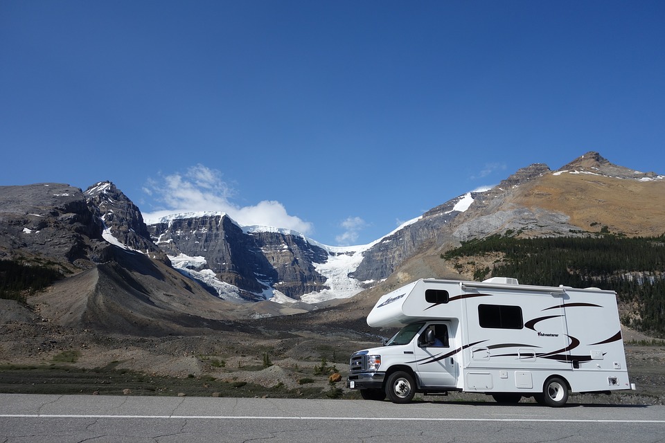 RV on road in front of snowy mountain